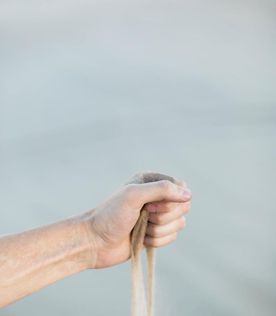 A hand letting fine sand run through the fingers